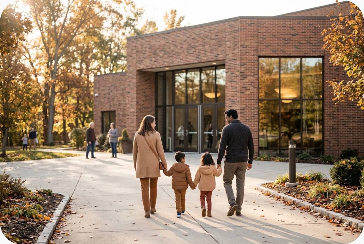 A mother, a father and two young children walk hand in hand toward a brick church.